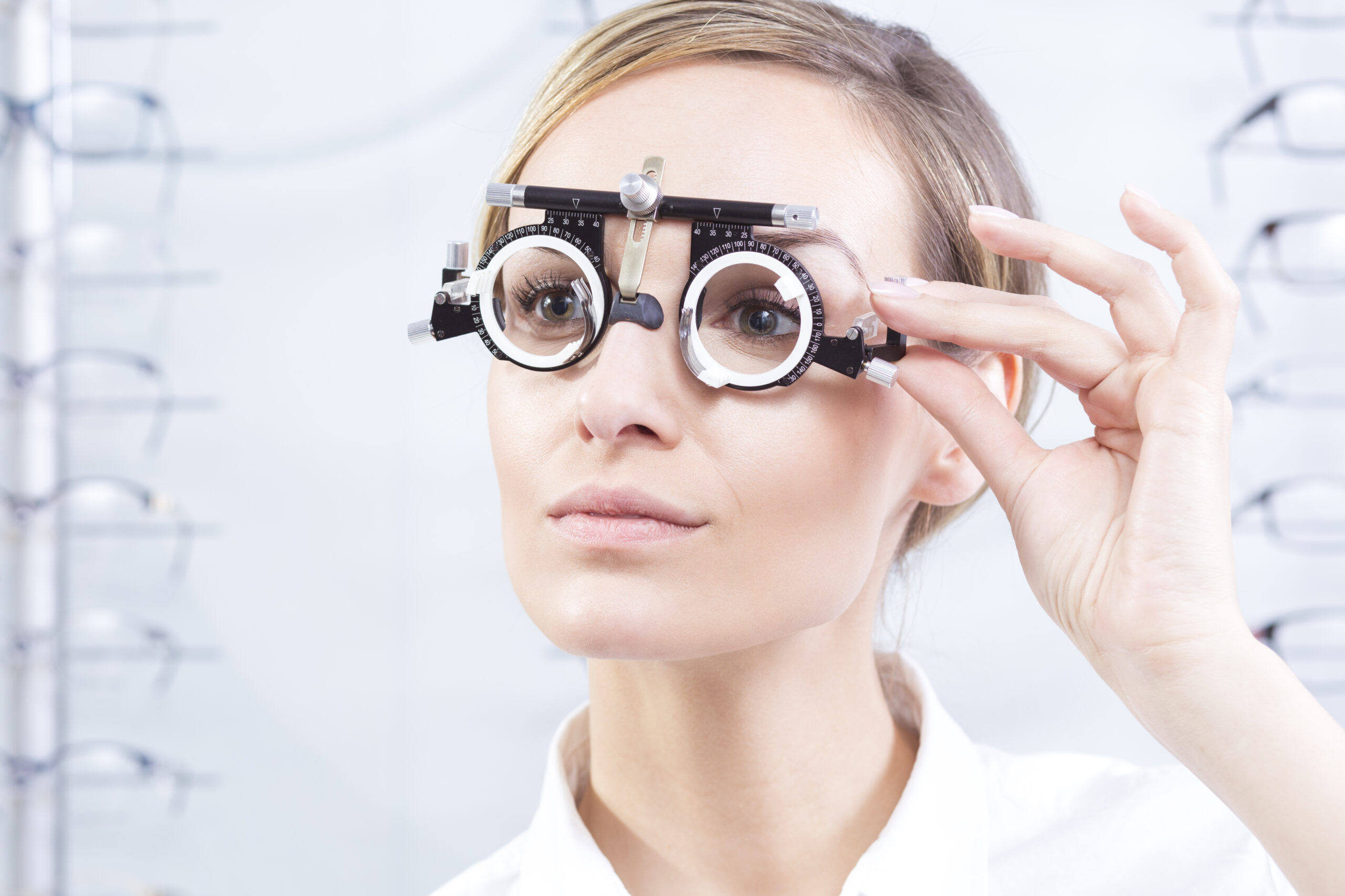 A woman adjusts a phoropter in an eye examination